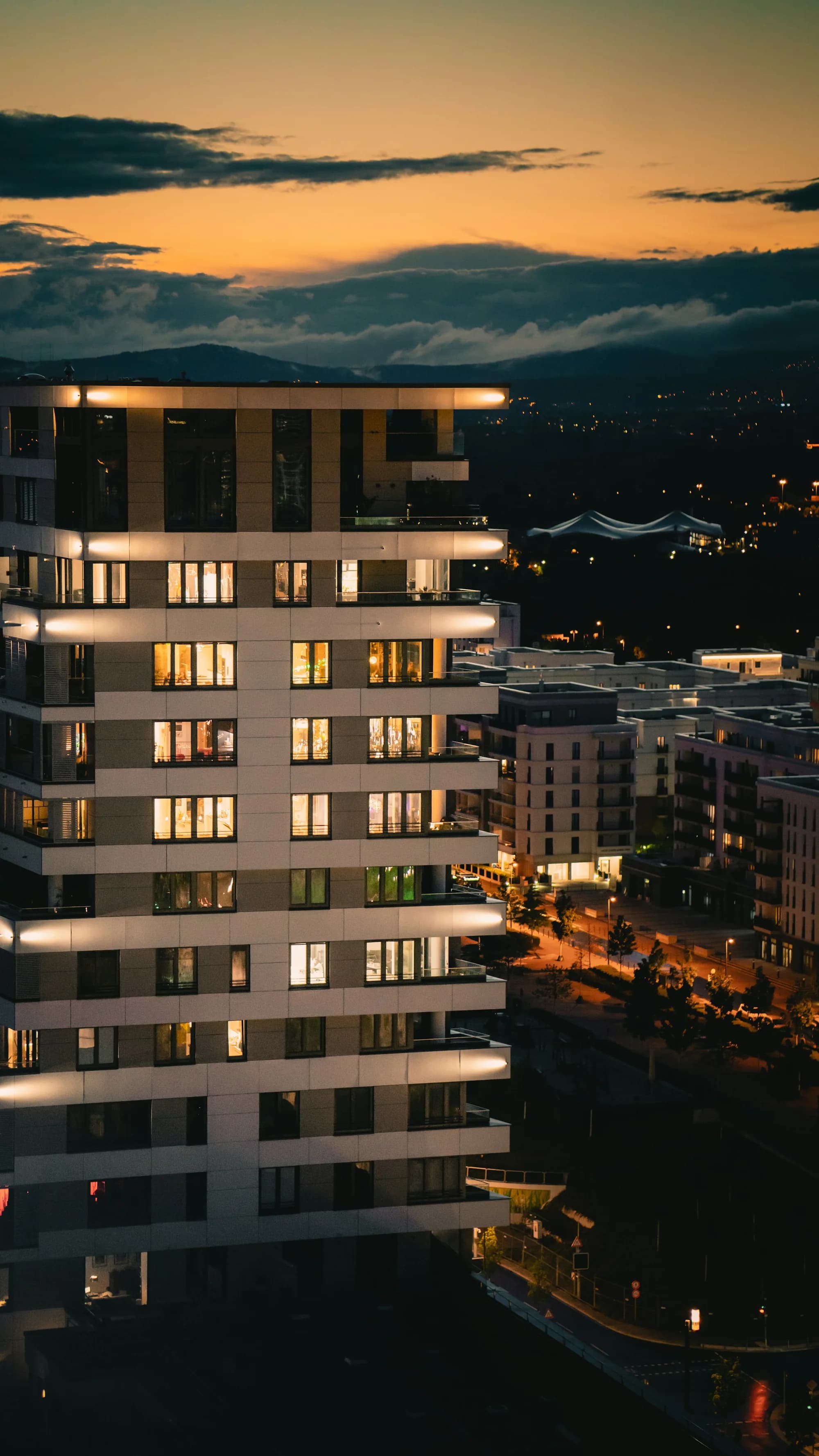 A residential tower at dusk with lit windows.